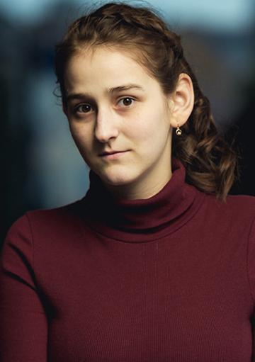 Maria Oprea in maroon turtleneck shirt